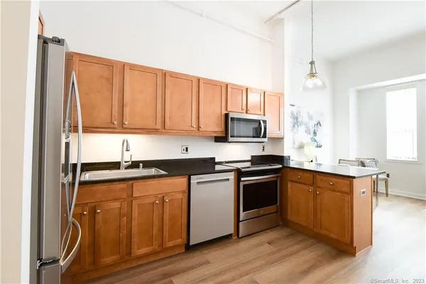 a kitchen with stainless steel appliances granite countertop a stove top oven a sink and dishwasher with wooden floor