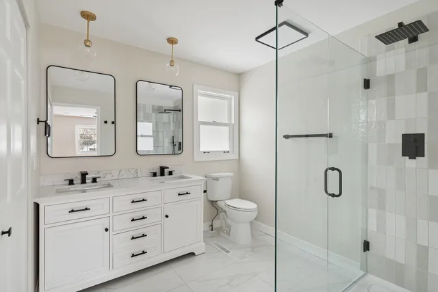 a bathroom with a double vanity sink toilet mirror and shower