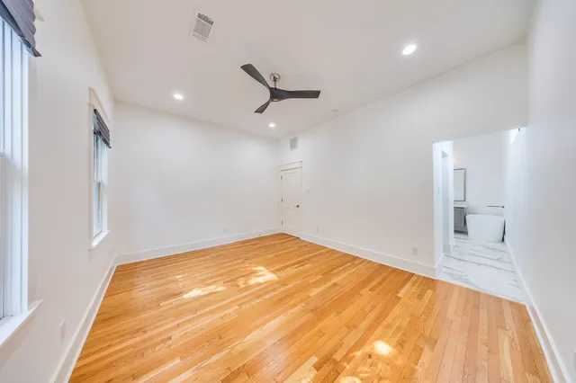 a view of empty room with wooden floor and fan