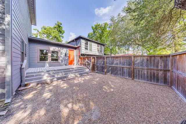 a view of a backyard with wooden fence and large trees