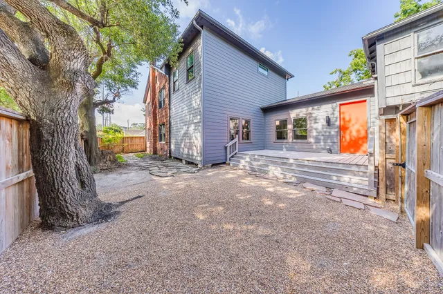 a backyard of a house with a large tree and wooden fence