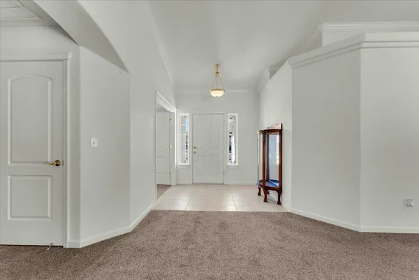 an empty room with chandelier fan and windows