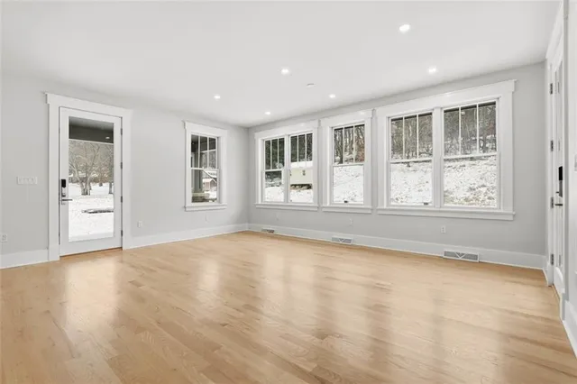 a view of an empty room with a window and wooden floor