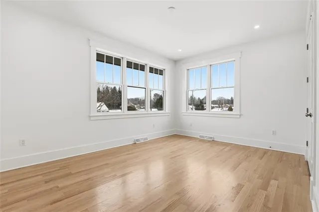 a view of an empty room with window and wooden floor