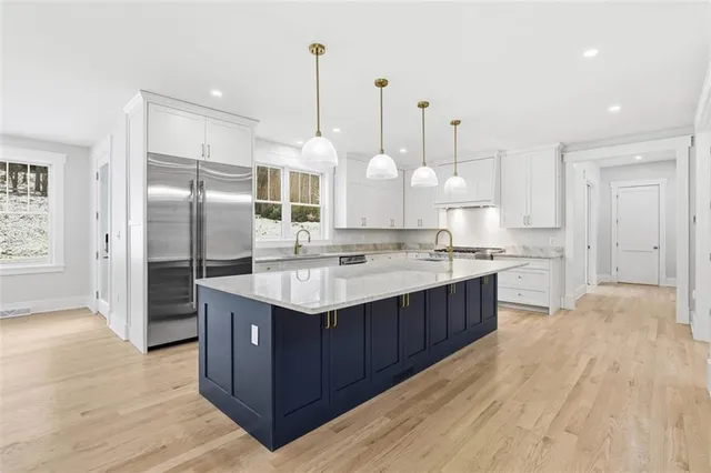 a kitchen with kitchen island granite countertop a sink and a refrigerator