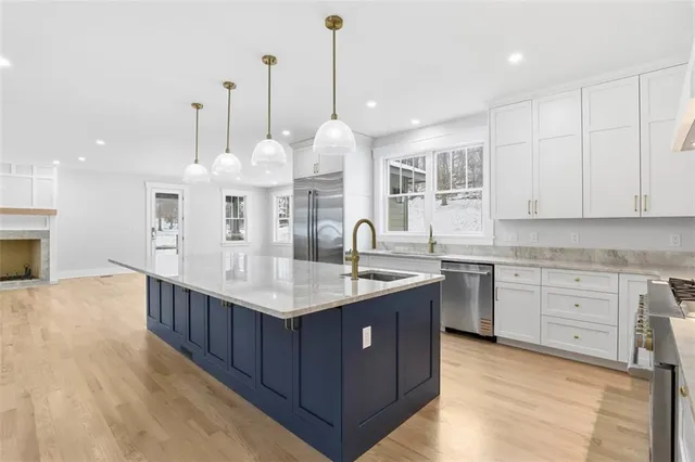 a kitchen with stainless steel appliances granite countertop a sink a center island a stove and a wooden floor