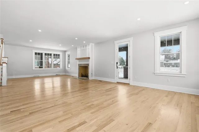a view of empty room with wooden floor and fireplace