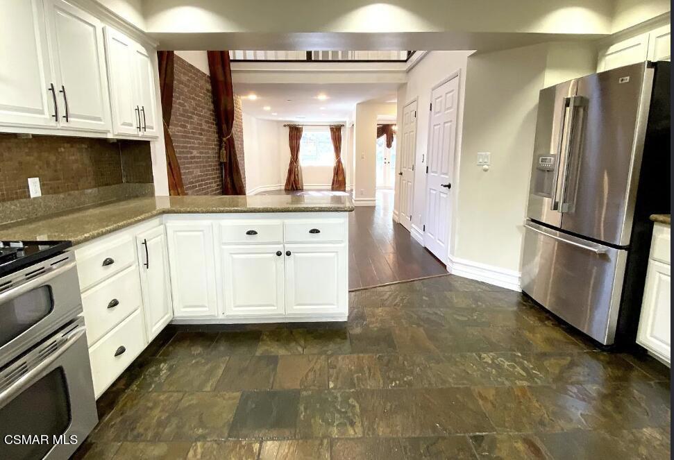 4130 Carrizal Road Woodland Hills, CA 91364 - Photo 11 of 33 a kitchen with granite countertop a refrigerator a stove a sink and white cabinets