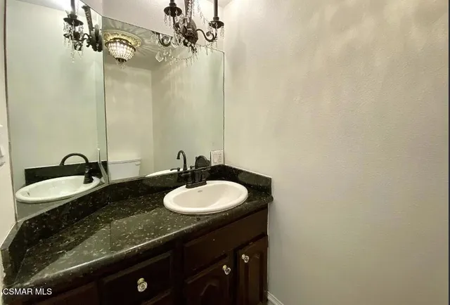 a bathroom with a granite countertop sink and a mirror
