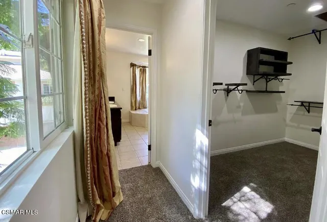 a view of a hallway with wooden floor and a bathroom
