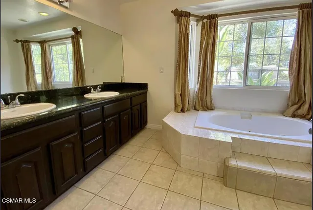 a spacious bathroom with a granite countertop sink a mirror and a bathtub