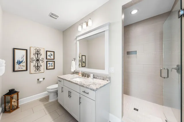 a bathroom with a granite countertop sink toilet a large mirror and a window