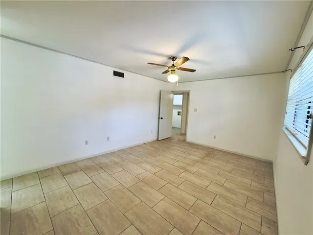 an empty room with windows and fan