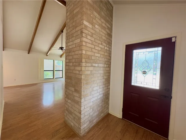 a view of a hallway with wooden floor and a bathroom