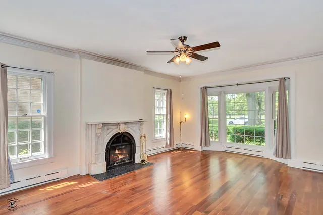 a view of a livingroom with a fireplace wooden floor and windows