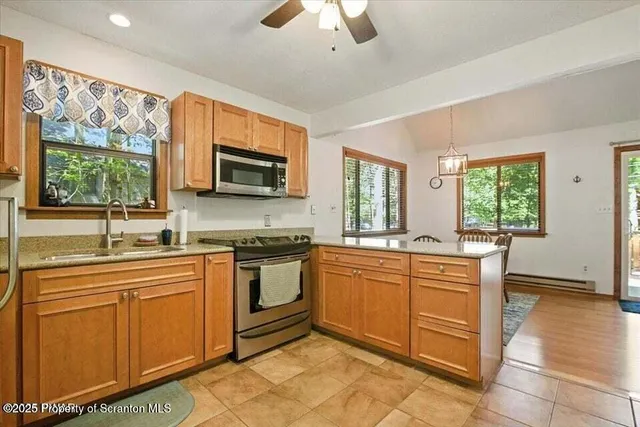 a kitchen with stainless steel appliances granite countertop a stove top oven a sink dishwasher a dining table and chairs with wooden floor