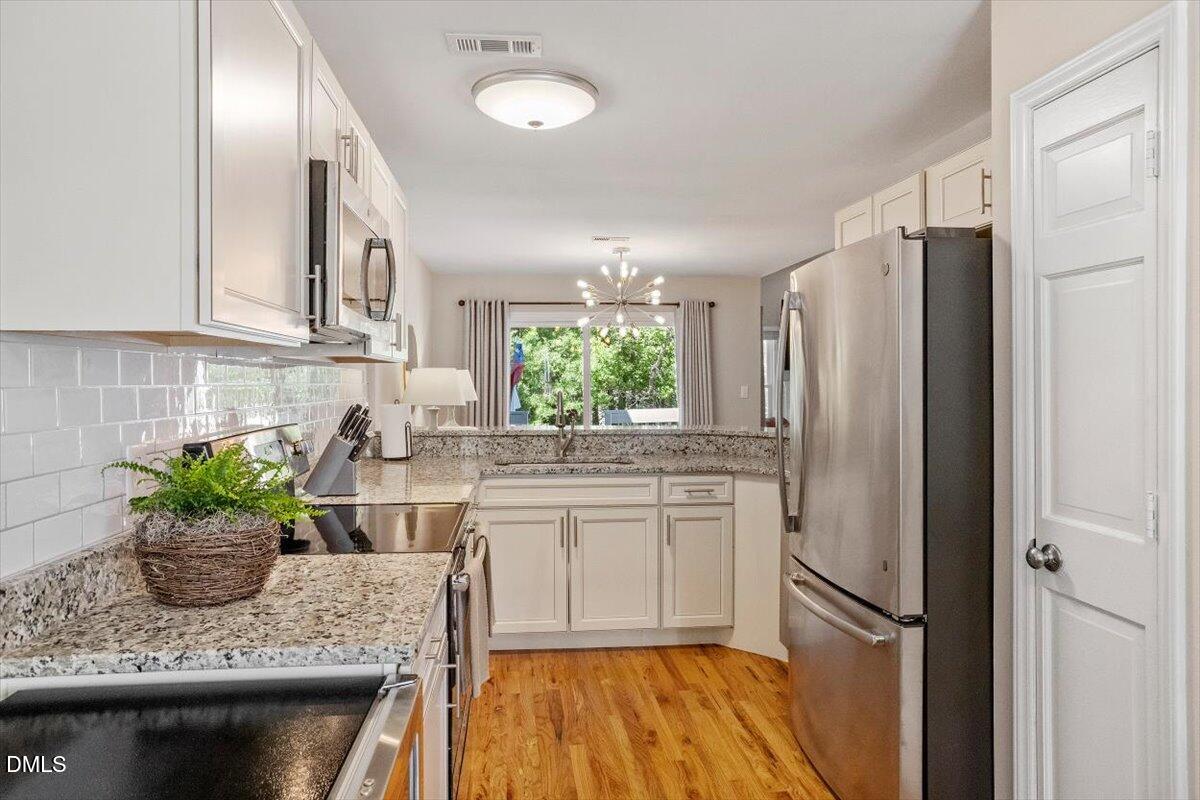 8321 Hempshire Place, Unit 103 Raleigh, NC 27613 - Photo 8 of 25 a kitchen with stainless steel appliances granite countertop a refrigerator sink and cabinets