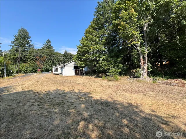 a view of dirt field with trees in the background