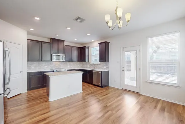 a large kitchen with a center island wooden floor stainless steel appliances and a window