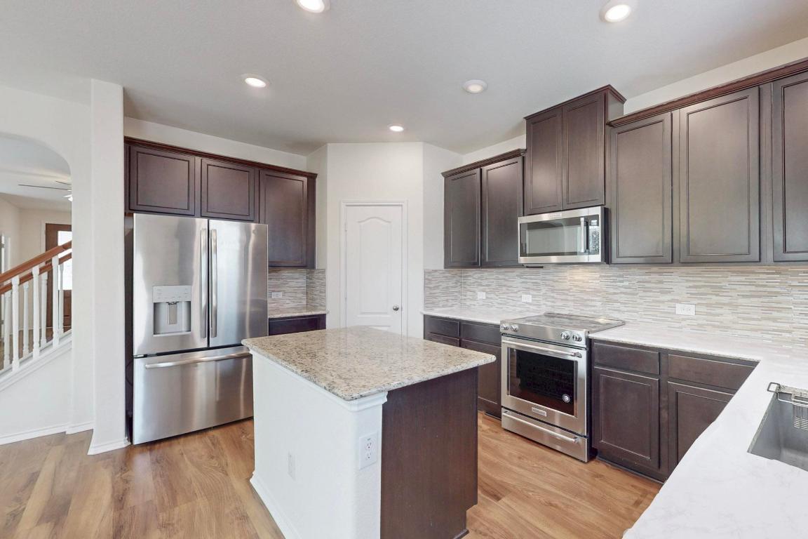 17308 Crazy Arm Road Round Rock, TX 78664 - Photo 7 of 22 a kitchen with stainless steel appliances granite countertop a sink stove and refrigerator