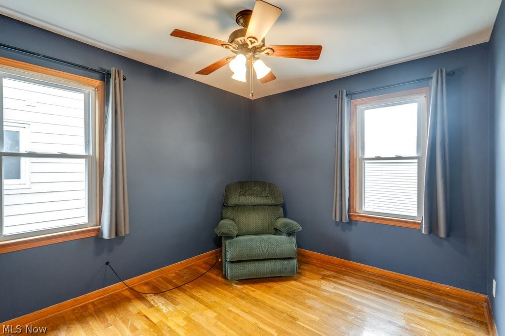 30000 Elgin Road Wickliffe, OH 44092 - Photo 14 of 30 Room featuring wood-finish flooring, two large windows with natural wood trim, and a ceiling fan with light fixture