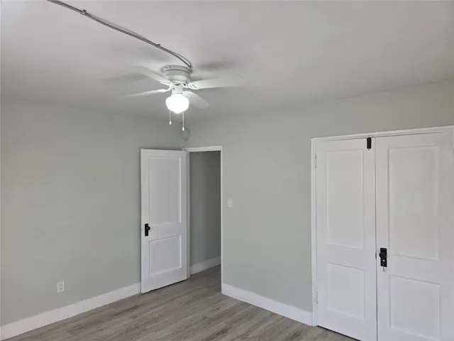 an empty room with wooden floor and ceiling fan