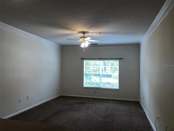 an empty room with a window and a fan