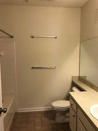 a bathroom with a granite countertop toilet and a sink