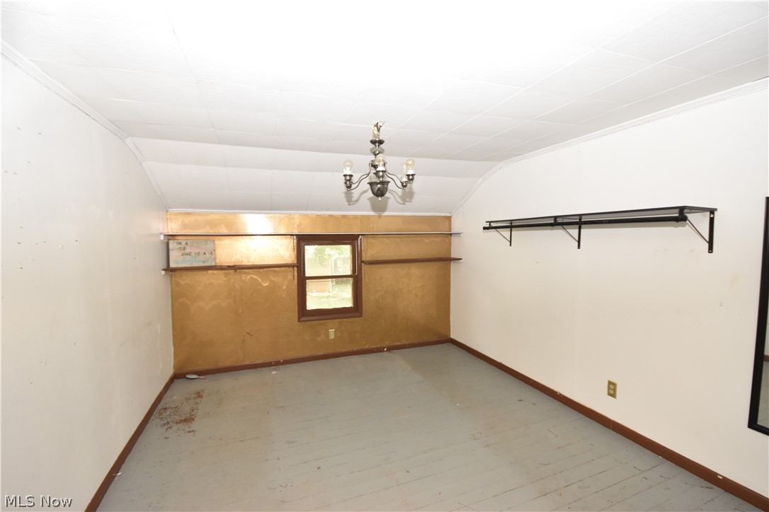 5694 Middle Ridge Road Madison, OH 44057 - Photo 12 of 27 Unfurnished room featuring hardwood / wood-style floors, vaulted ceiling, and an inviting chandelier