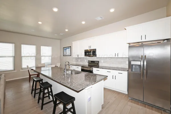 a kitchen with a table chairs microwave and refrigerator