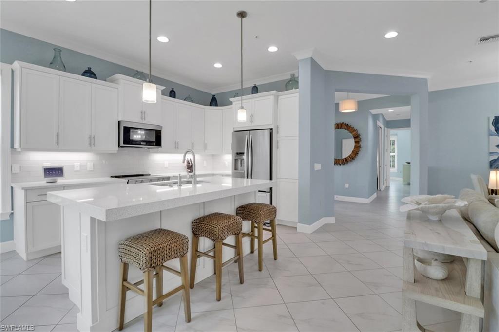 6509 Dominica Drive, Unit 101 Naples, FL 34113 - Photo 9 of 33 a open kitchen with stainless steel appliances granite countertop a sink a stove a refrigerator and a dining table with white cabinets