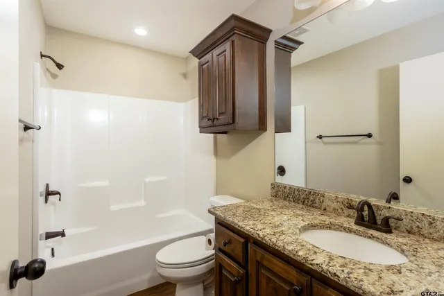 a bathroom with a granite countertop sink toilet and shower