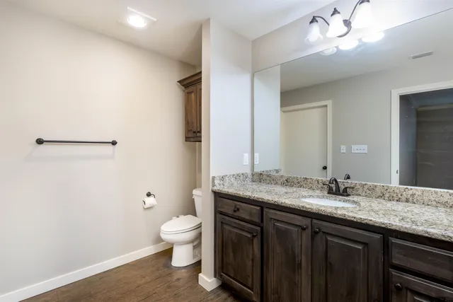 a bathroom with a granite countertop sink a toilet and a mirror
