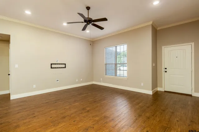 a view of an empty room with wooden floor and a window