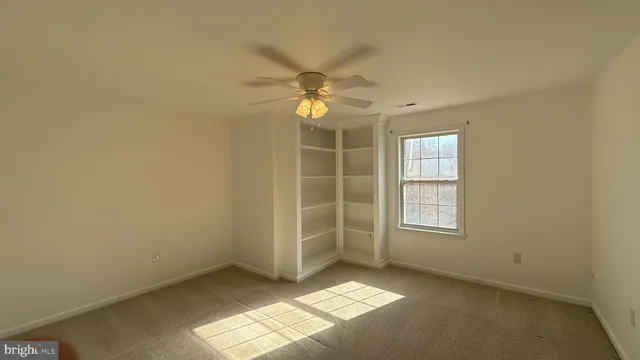 an empty room with a window and a fan