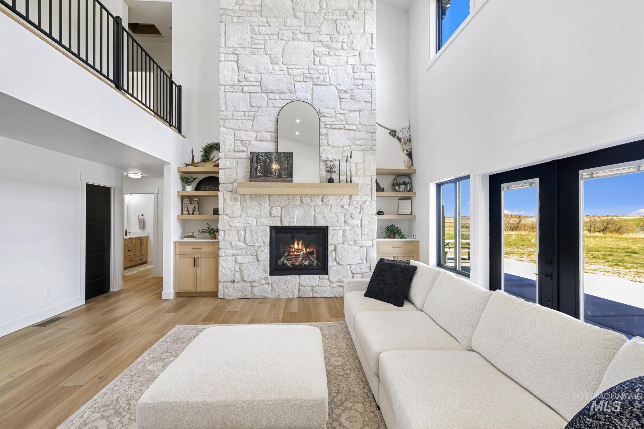 4288 North 2400 East Filer, ID 83328 - Photo 17 of 50 Living area featuring a high ceiling, light wood-type flooring, a stone fireplace, and healthy amount of natural light