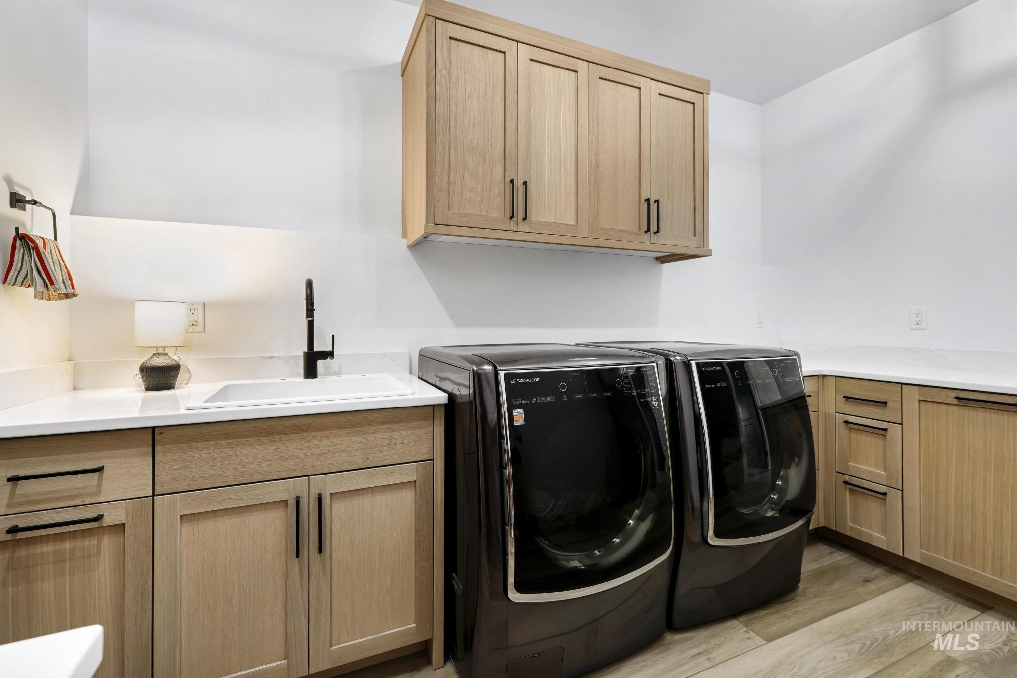 4288 North 2400 East Filer, ID 83328 - Photo 20 of 50 Laundry area with light wood finished floors, washer and clothes dryer, and cabinet space