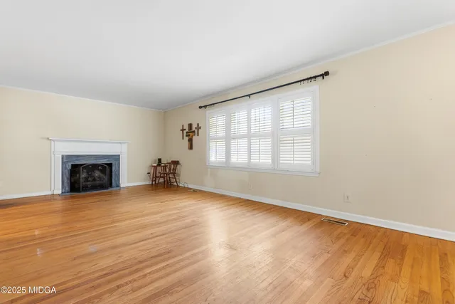 an empty room with wooden floor fireplace and windows