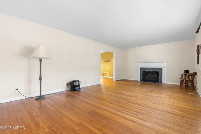a view of an empty room with wooden floor and a fireplace