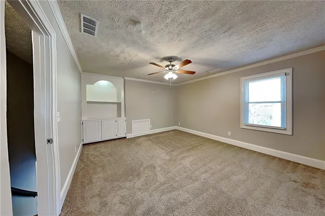 an empty room with windows and chandelier fan