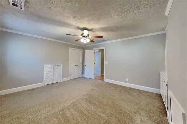 an empty room with chandelier fan and windows