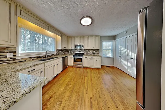a large kitchen with stainless steel appliances granite countertop a stove a sink and a refrigerator