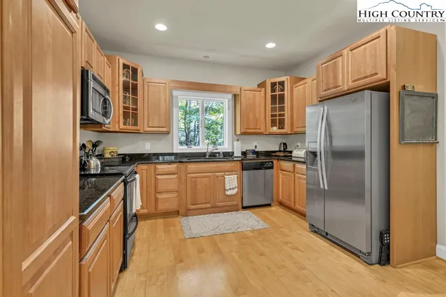 a kitchen with granite countertop stainless steel appliances a refrigerator a stove top oven and a sink
