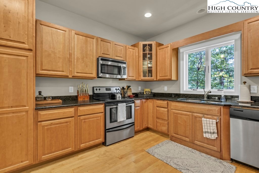 100 Northridge Road Beech Mountain, NC 28604 - Photo 10 of 32 a kitchen with stainless steel appliances granite countertop a stove top oven a sink dishwasher and white cabinets with wooden floor