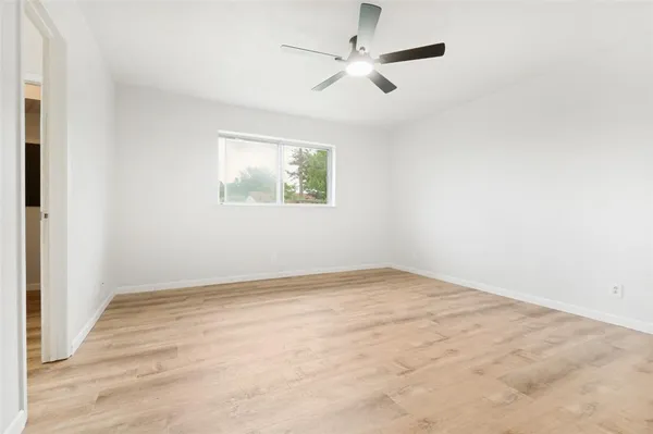 an empty room with a window and a ceiling fan