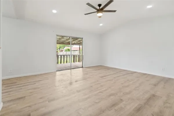 an empty room with wooden floor fan and windows