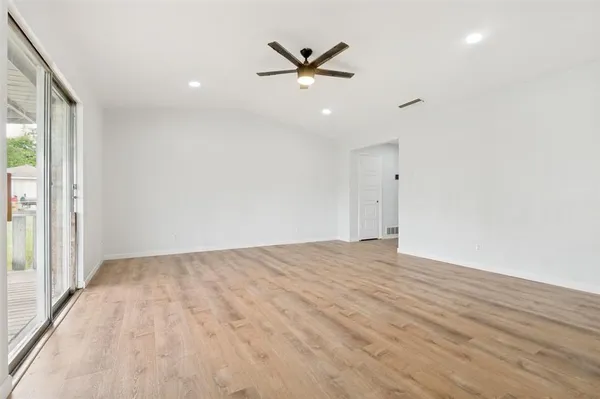 an empty room with wooden floor and ceiling fan