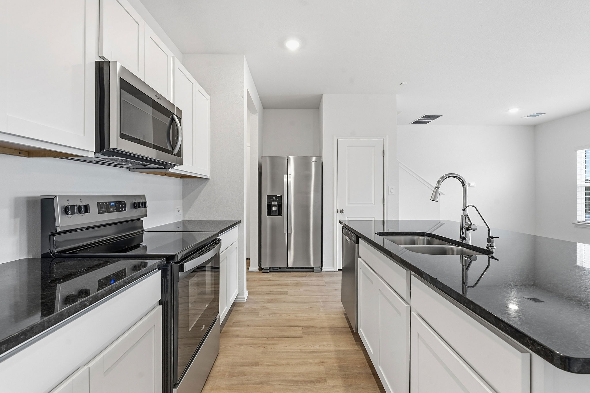 164 Cinnabar Lane, Unit 4 Kyle, TX 78640 - Photo 9 of 23 Contemporary kitchen featuring stainless steel appliances, dark countertops, white cabinetry, wood-finish flooring, and recessed lighting