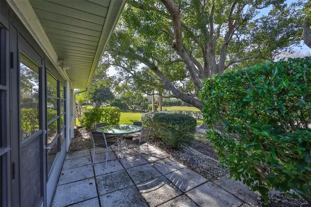 a view of a patio with table and chairs potted plants and large tree