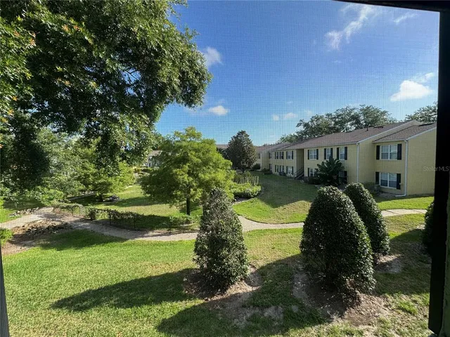 an empty room with a chandelier fan and windows